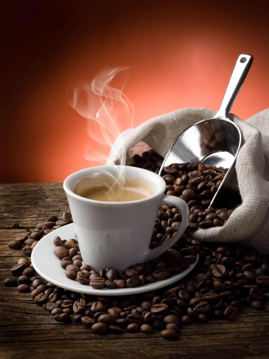 Cup of coffee with steam coming out of a bag of coffee beans