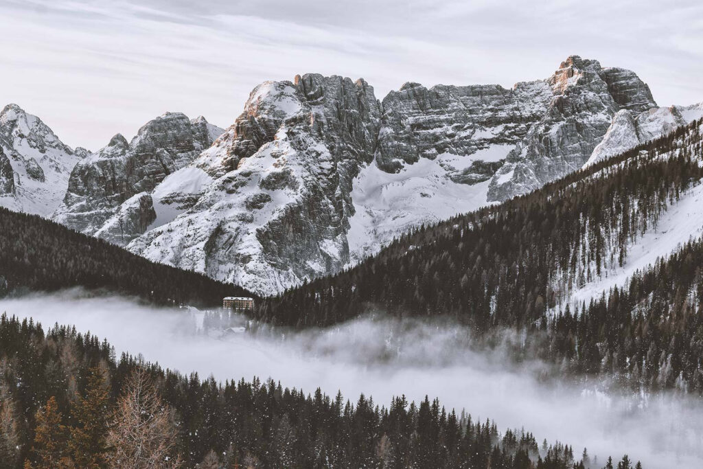 Snowy mountain range with trees and a building Snowy mountain range with trees and a building