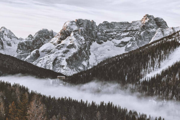 Snowy mountain range with trees and a building Snowy mountain range with trees and a building