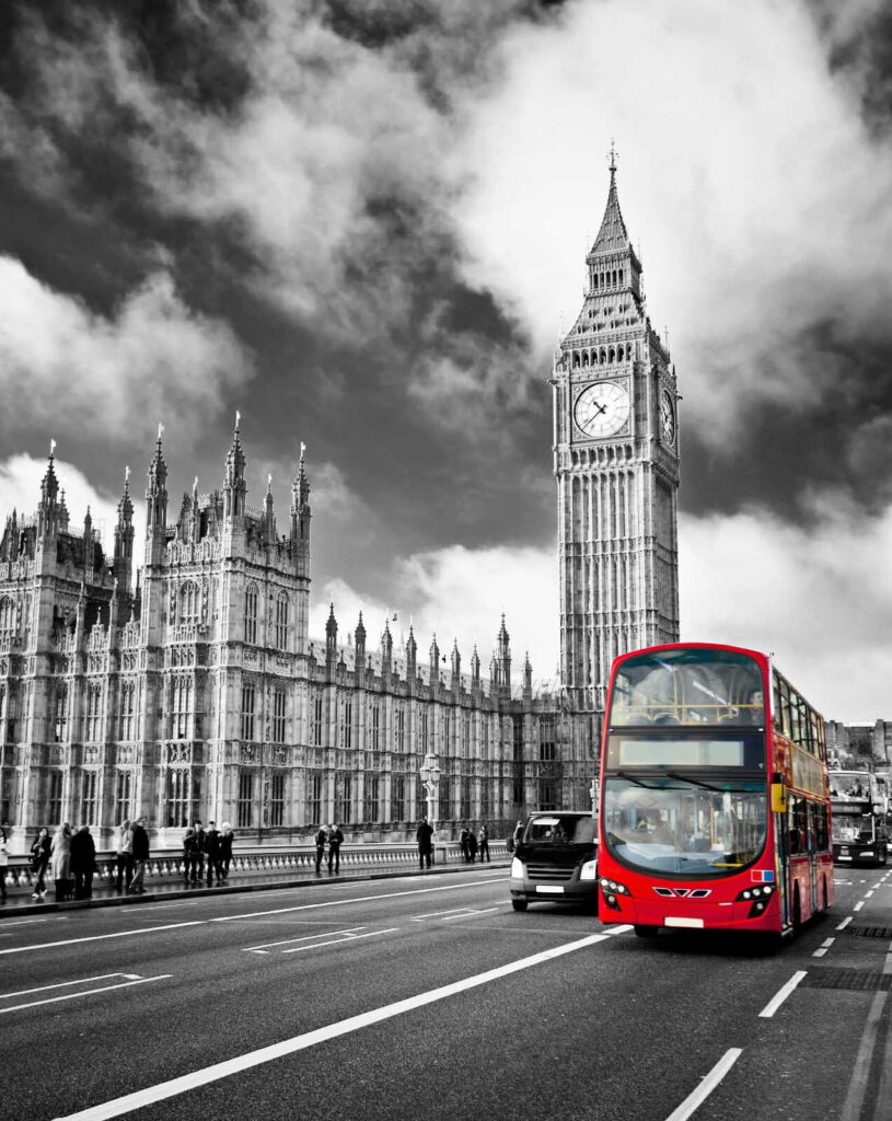 Red double decker bus on a street with a clock tower in the background Red double decker bus on a street with a clock tower in the background